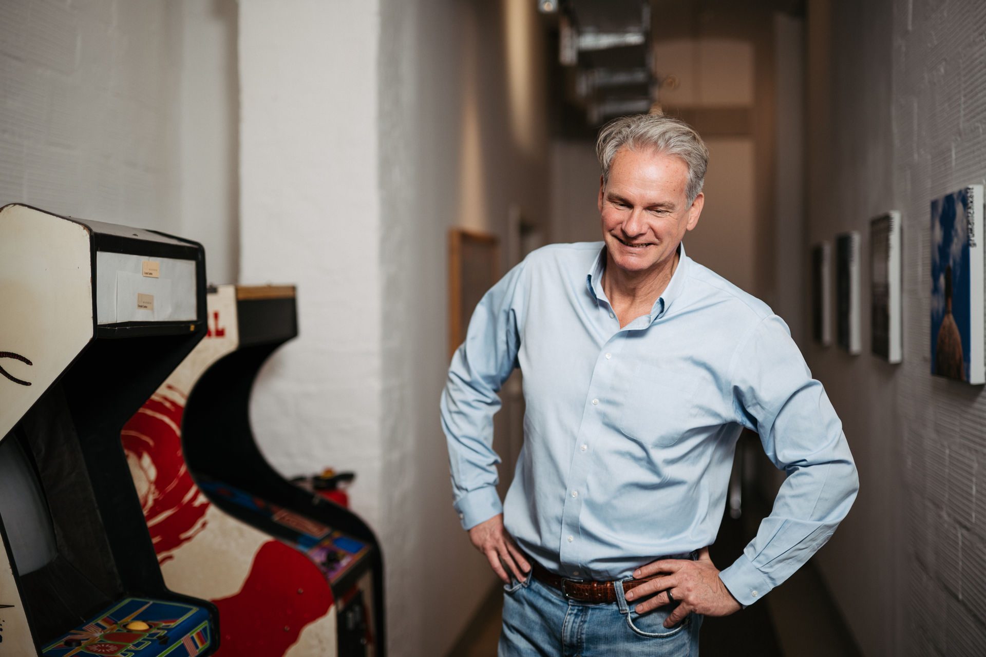 Jochen Hummel standing in a loft corridor beside an old arcade cabinet