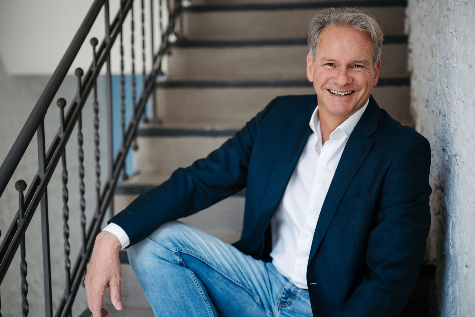 Jochen Hummel sitting on a staircase, laughing