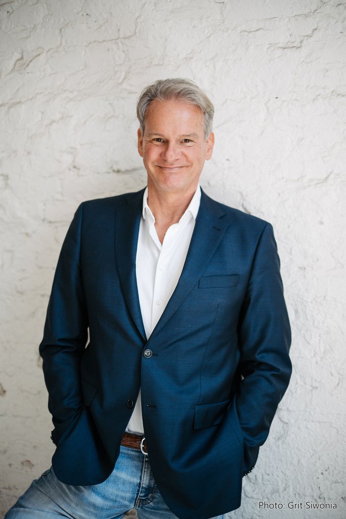 Portrait of Jochen Hummel against a white wall, upright format